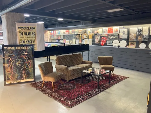 Sitzecke mit Vintage-Sesseln, Perserteppich sowie Jimi-Hendrix- und Beatles-Plakaten im Vinylkeller