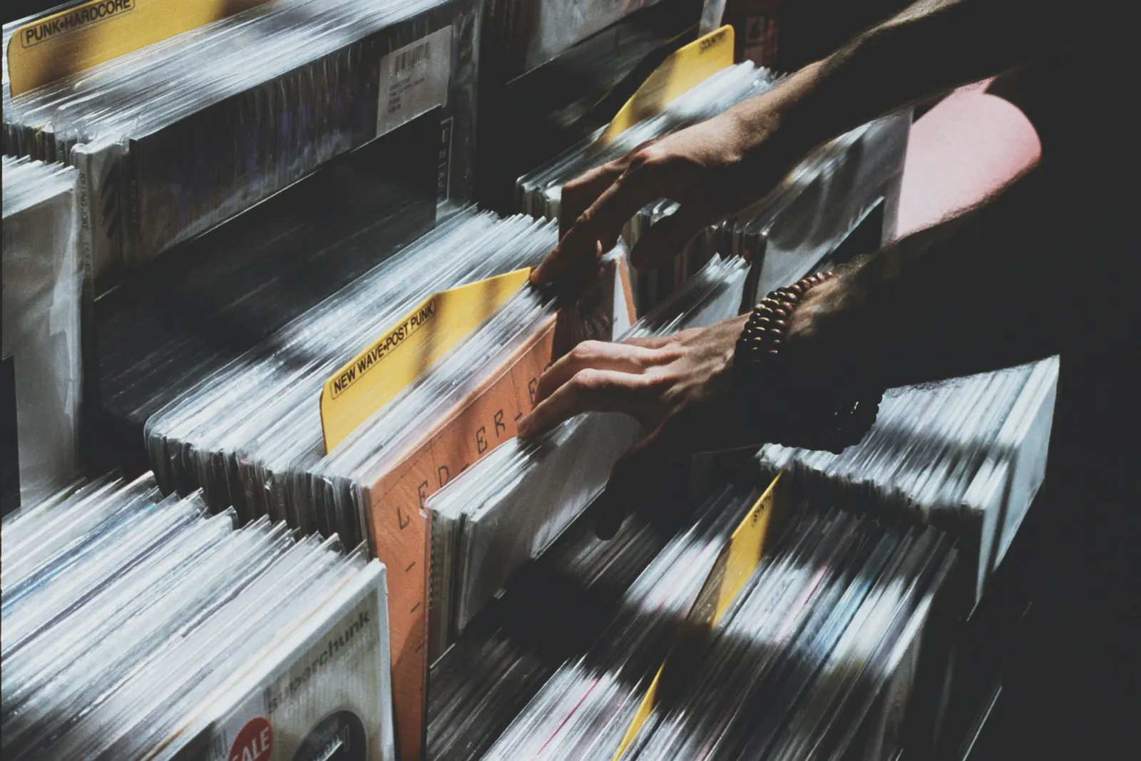 Hände blättern durch eine Kiste mit gebrauchten Schallplatten